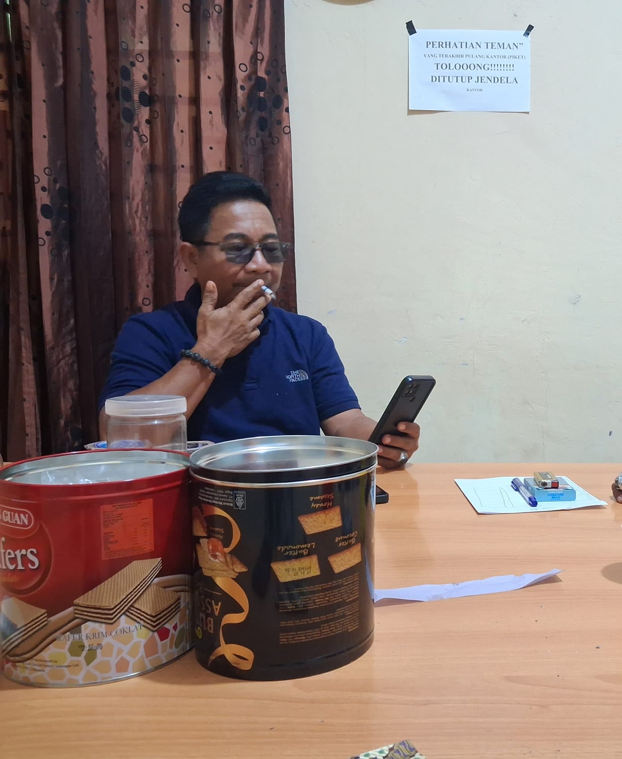 Kepala Desa Topogaro saat ditemui di dalam ruangan sedang memegang ponsel dan duduk di meja kerja