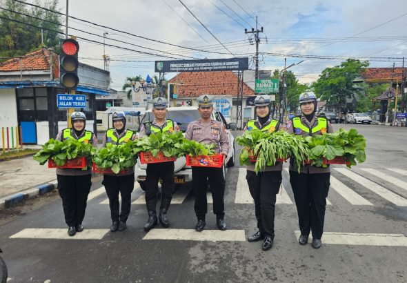 Personel Satlantas Polres Sampang membagikan sayuran segar hasil Program Pekarangan Pangan Lestari kepada pengendara di Monumen Trunojoyo