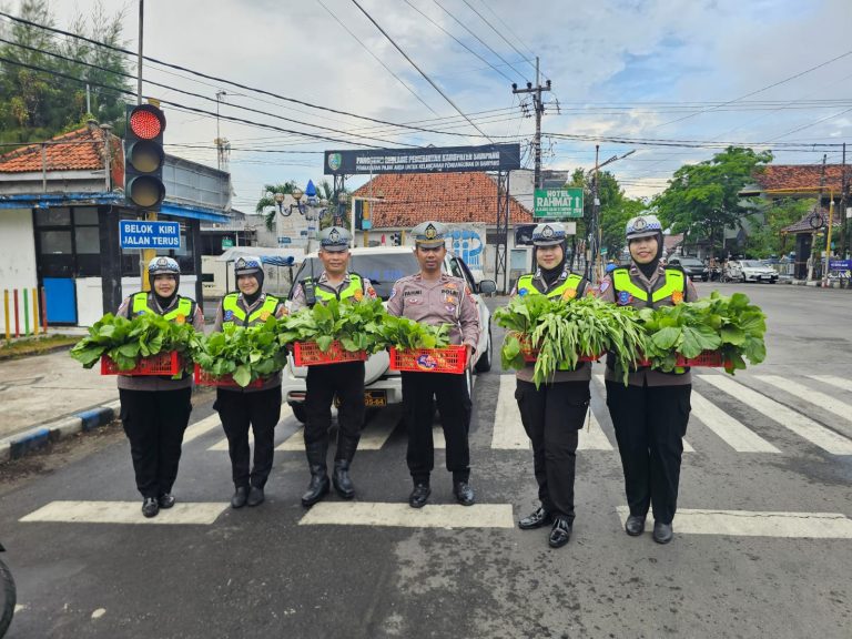 Personel Satlantas Polres Sampang membagikan sayuran segar hasil Program Pekarangan Pangan Lestari kepada pengendara di Monumen Trunojoyo